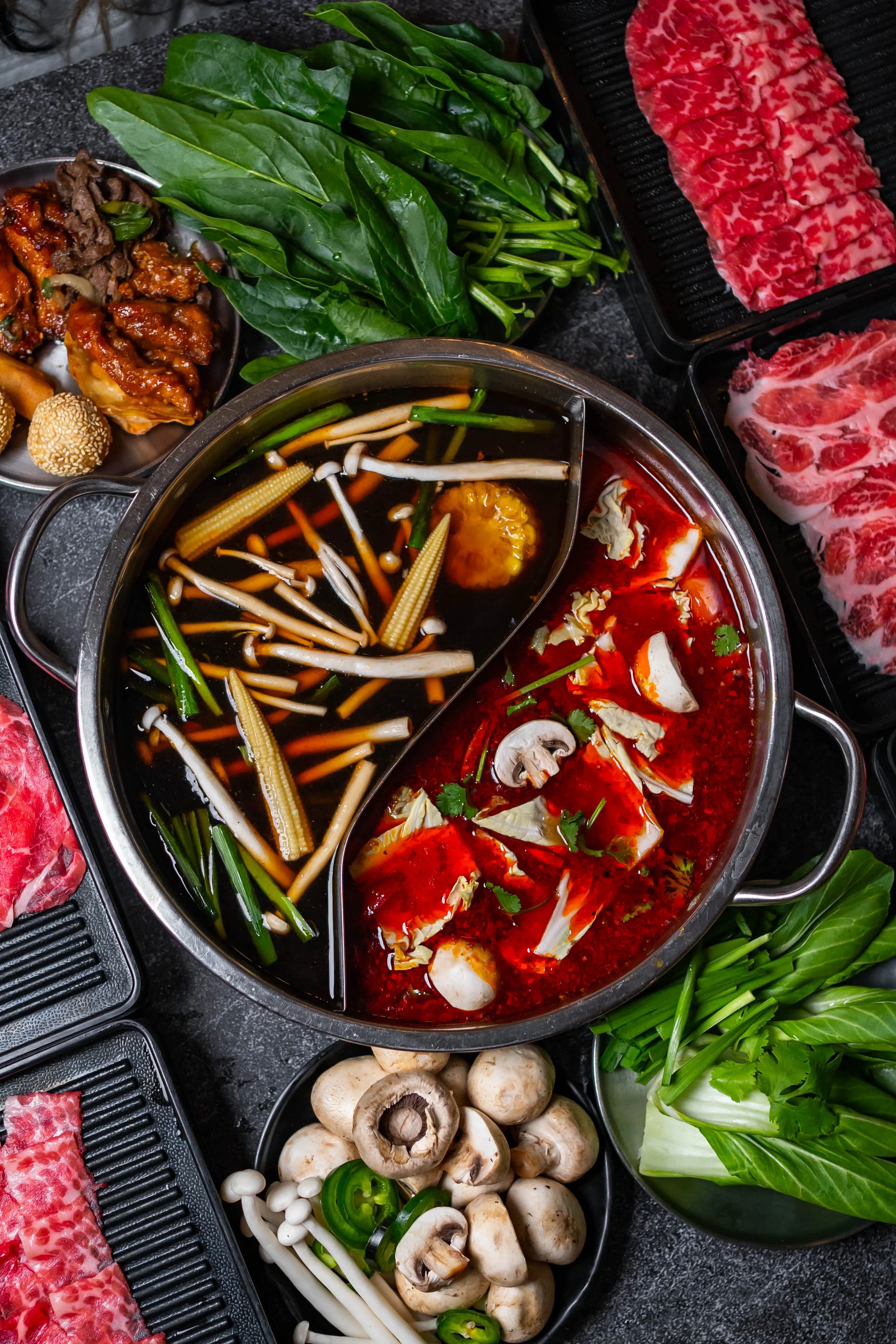 Split broth pot with meats and vegetables